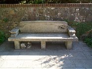 A little dog lies curled up beneath this fine stone bench seat.