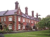 St. John's Hospital (north). Red brick with stone dressings. 2 storeys. Built in Tudor- Gothic style with Jacobean porches. Slate roofs with chimney clusters. Shaped Jacobean gables. Leaded lattice casement windows. Dated 1862 on rainwater heads. Architects. H.C. Brown and T. Stopher.    SU 485 294